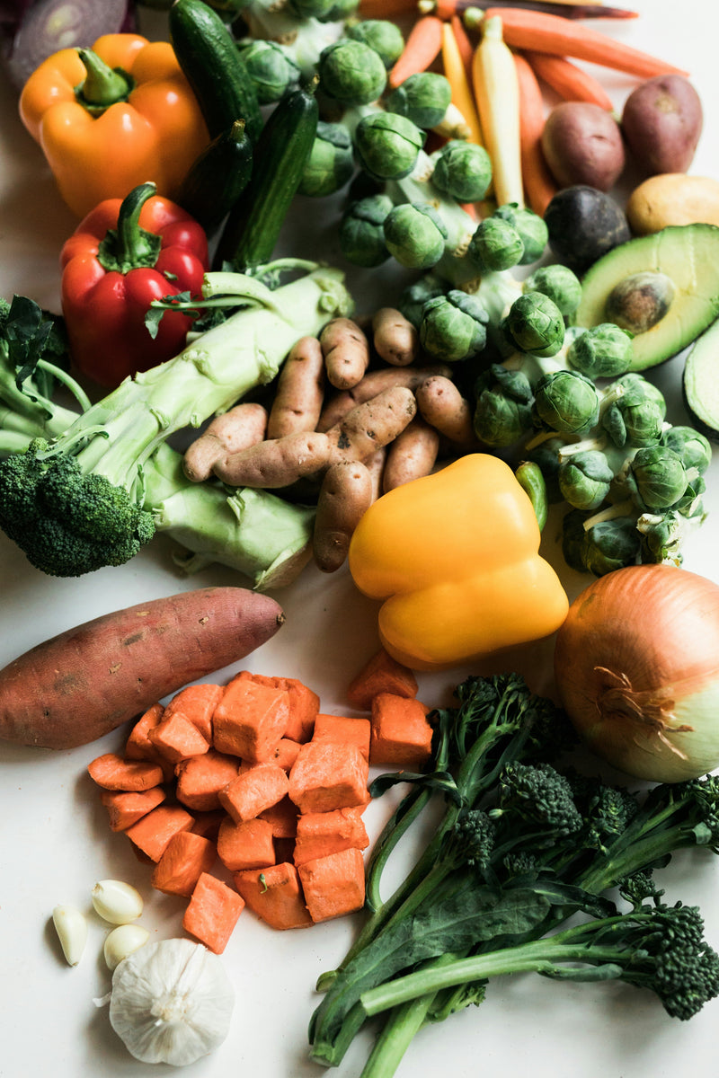 Low-FODMAP foods arranged on a table including vegetables, rice, and fruits